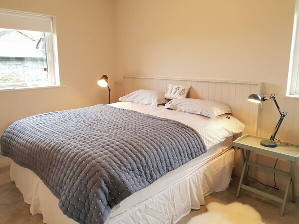 A bedroom with a bed, bedside tables, and a window.