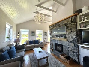 A spacious living room with a stone fireplace, a sofa set, a coffee table, and a television.