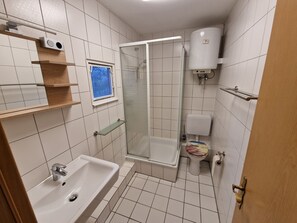 Kylpyhuone, jossa on pesuallas, wc, suihku ja ikkuna.