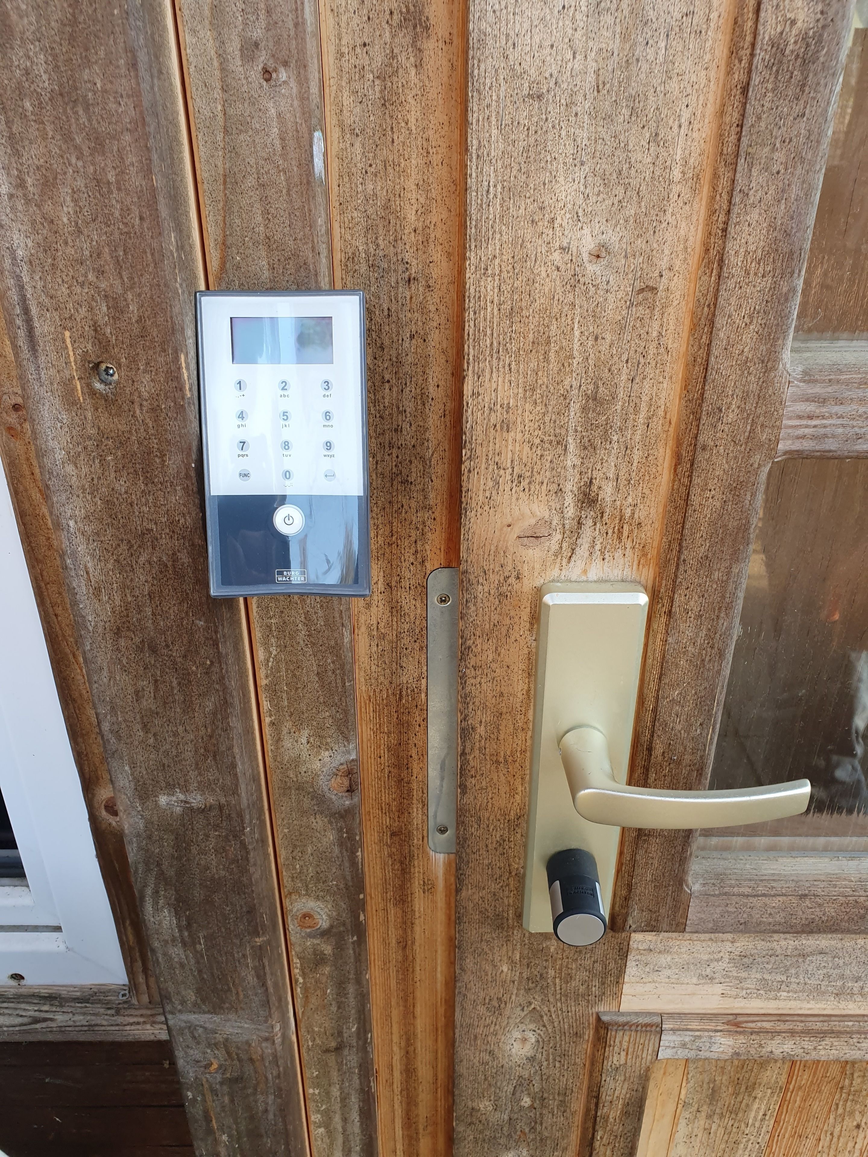 En dörr av trä med ett digitalt kodlås och ett handtag.