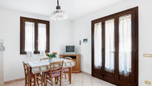 A dining area with a wooden table, chairs, and a television on a wooden cabinet. - Just 500 m from the sandy beach - Primula 2 (Marina di Campo)
