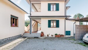 A two-story house with a staircase leading to the upper floor, a gravel driveway, and potted plants at the entrance. - Just 500 m from the sandy beach - Primula 2 (Marina di Campo)