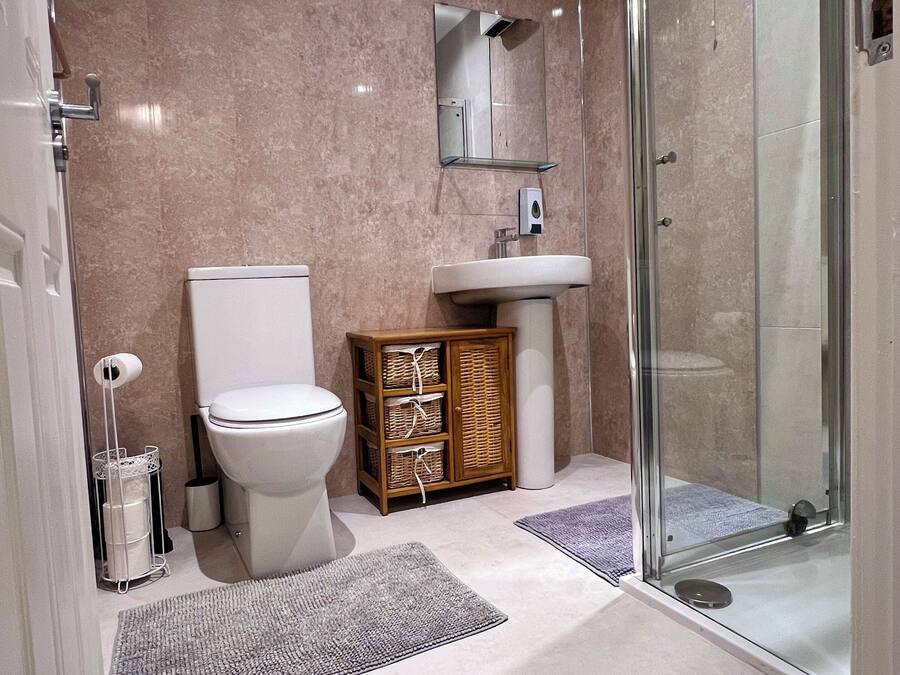 A modern bathroom with a toilet, sink, and glass shower enclosure.
