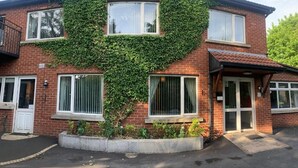 A two-story house with a heart-shaped ivy design on the front wall, a front door, and a small porch. - Ashfield Bed and Breakfast (Belfast)