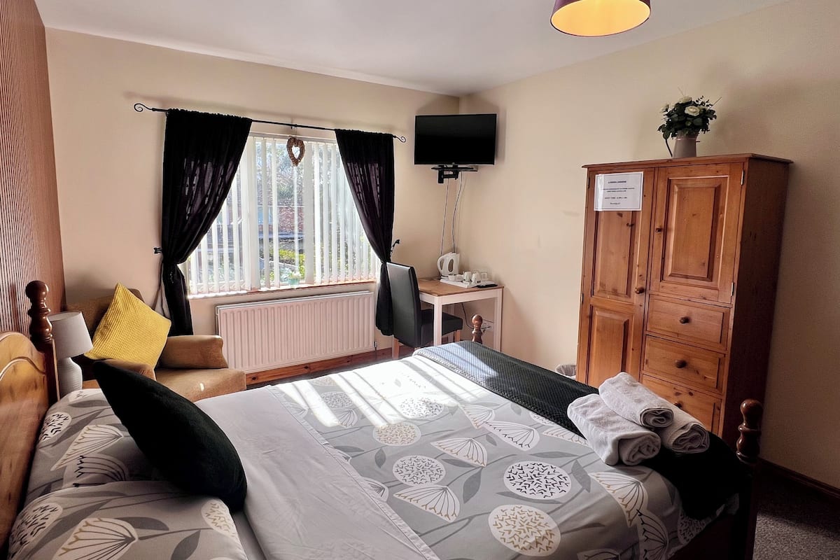 A hotel room with a bed, a desk, a television, a cabinet, and a window with curtains.