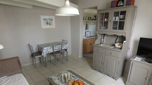 Un espace de vie compact comprenant un coin repas, une kitchenette et un téléviseur.