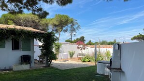 Il s’agit d’une propriété résidentielle dotée d’un patio couvert, d’un petit jardin et d’une façade extérieure blanche.