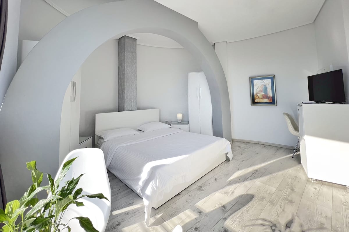 Un dormitorio moderno con una cama grande, un escritorio, una silla y un televisor.