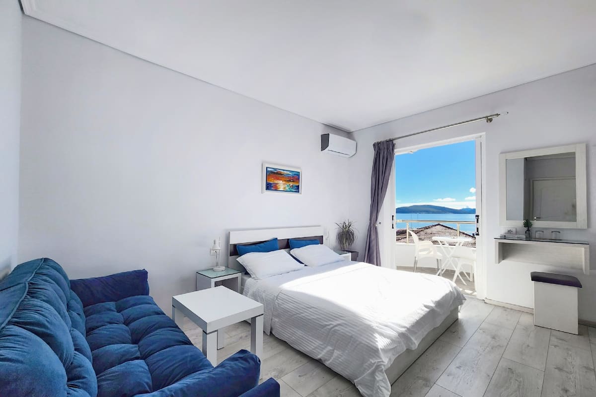 Un dormitorio moderno con cama, sofá, una mesita y vista al mar.