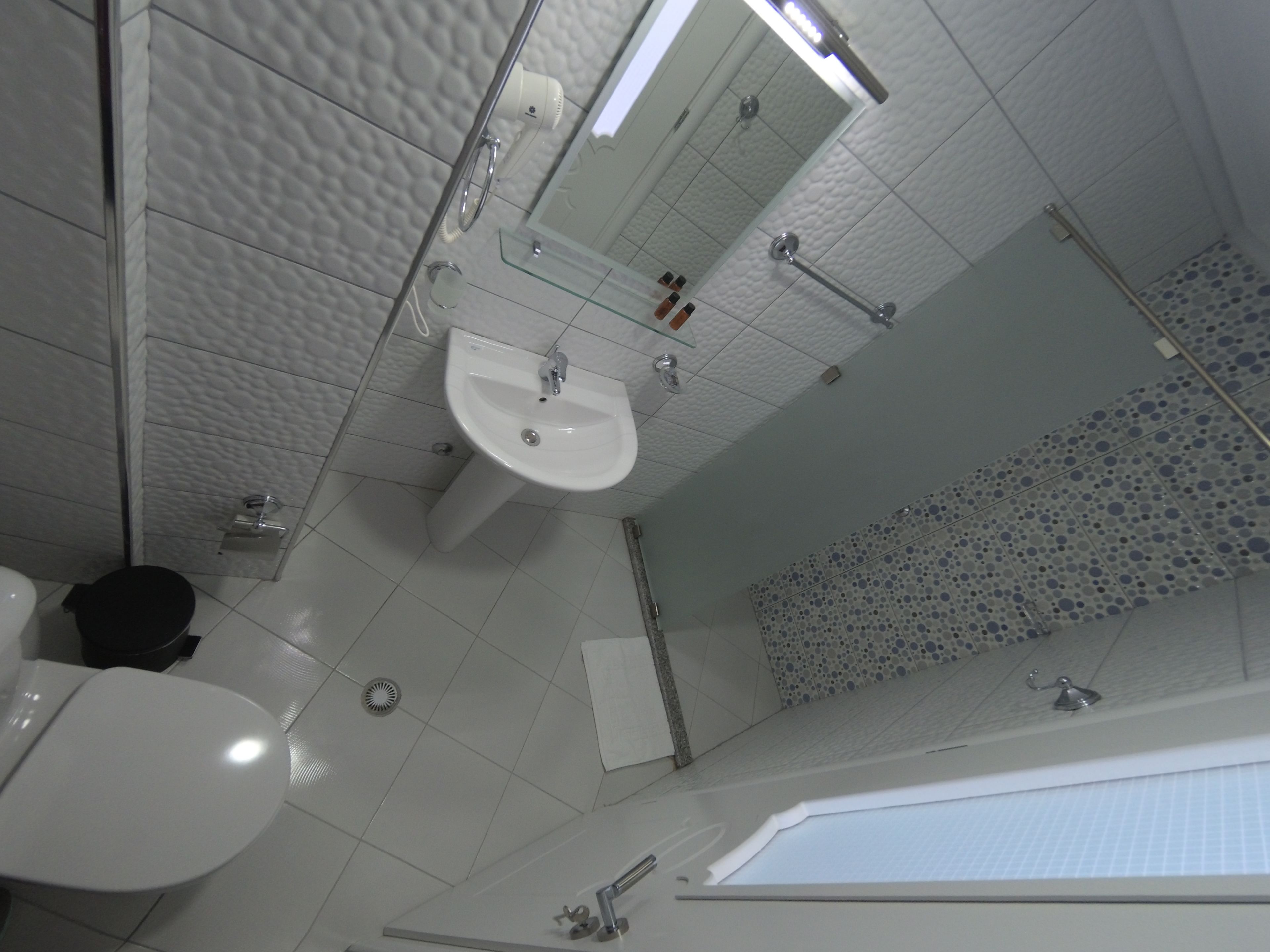A bathroom with a white sink, mirror, and toilet.