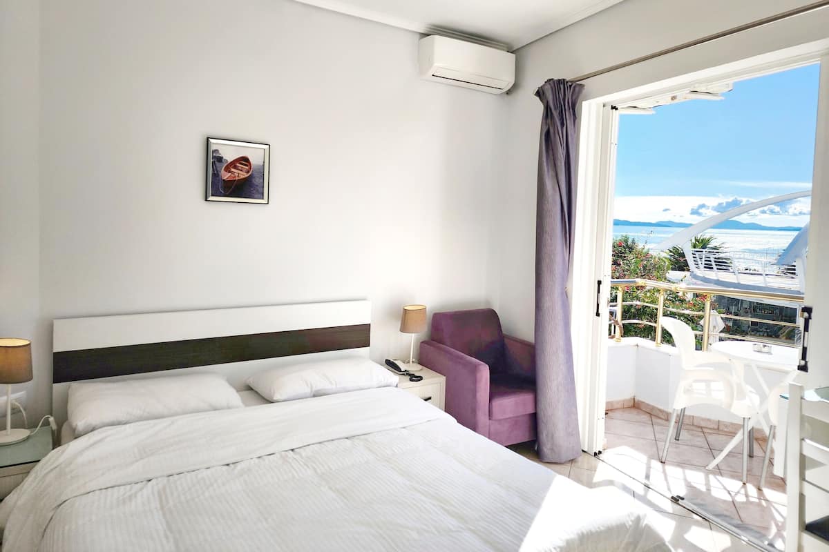 Habitación de hotel con cama, una silla, un escritorio y balcón con vista al mar y un crucero.