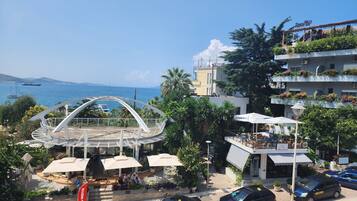 A coastal view with a modern building featuring outdoor seating and a view of the sea.