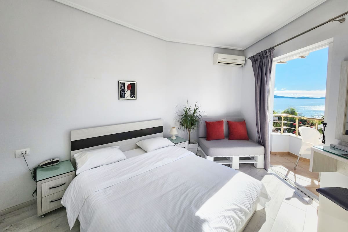 Un dormitorio con cama, mesita de noche y vista al mar.