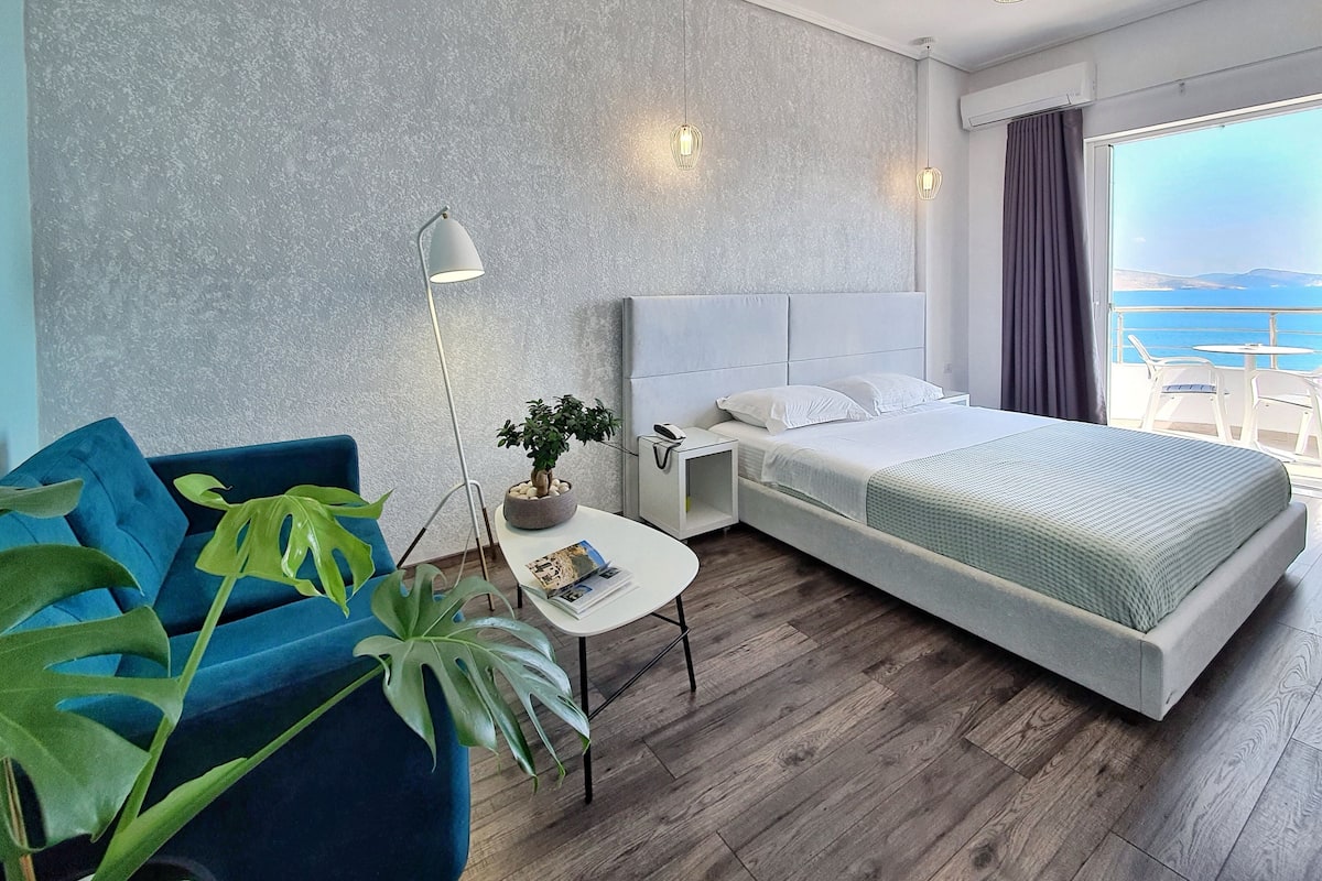 Habitación de hotel moderna con una cama grande, un escritorio, una silla y vistas al mar.