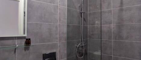 Une salle de bain moderne avec une douche à parois de verre, un lavabo blanc et des toilettes.