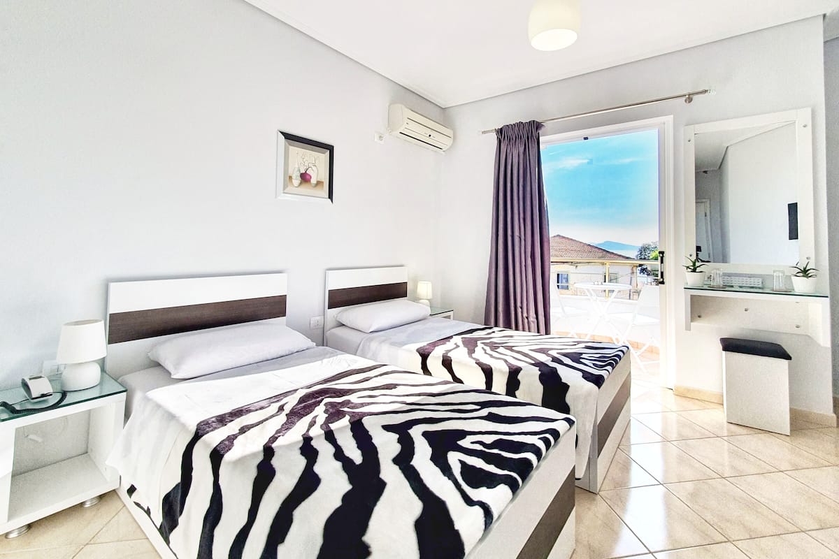 Habitación de hotel con dos camas, baño y vistas al exterior.