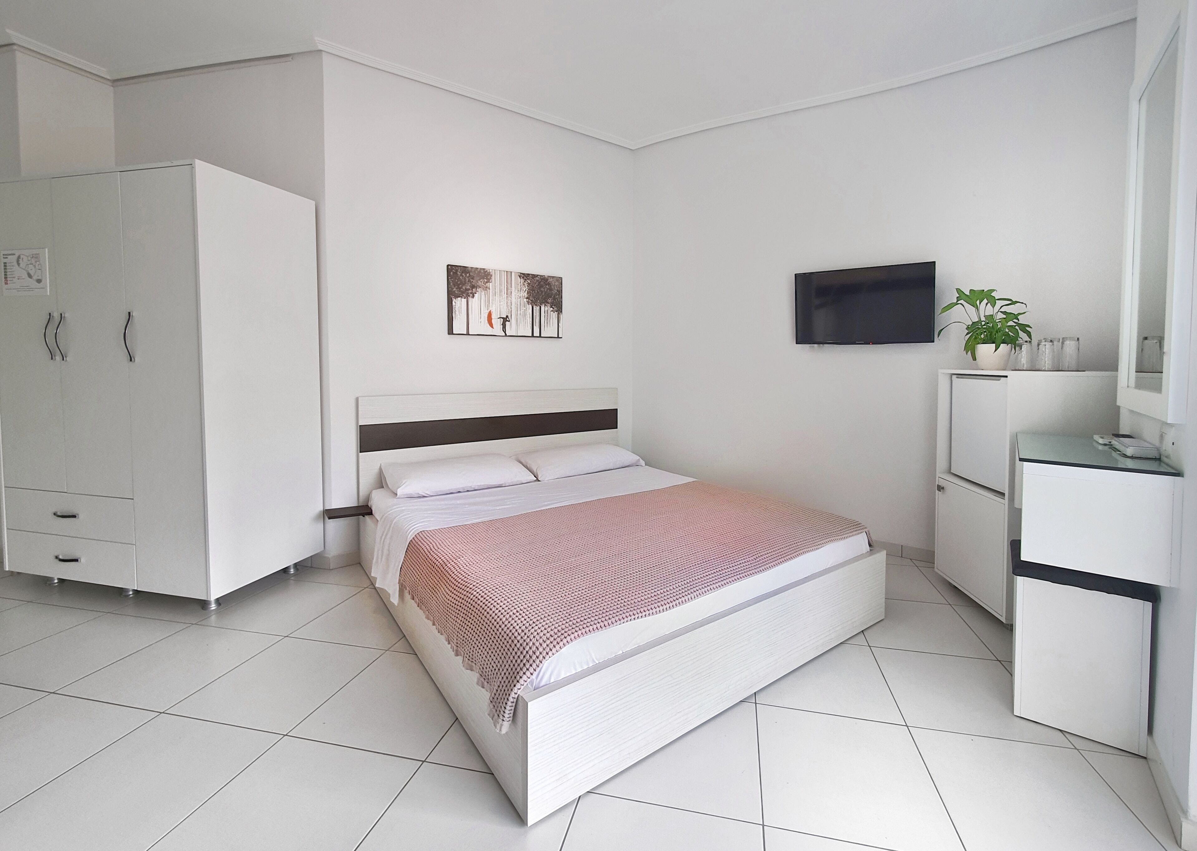 A modern bedroom with a bed, wardrobe, TV, and a small desk area.