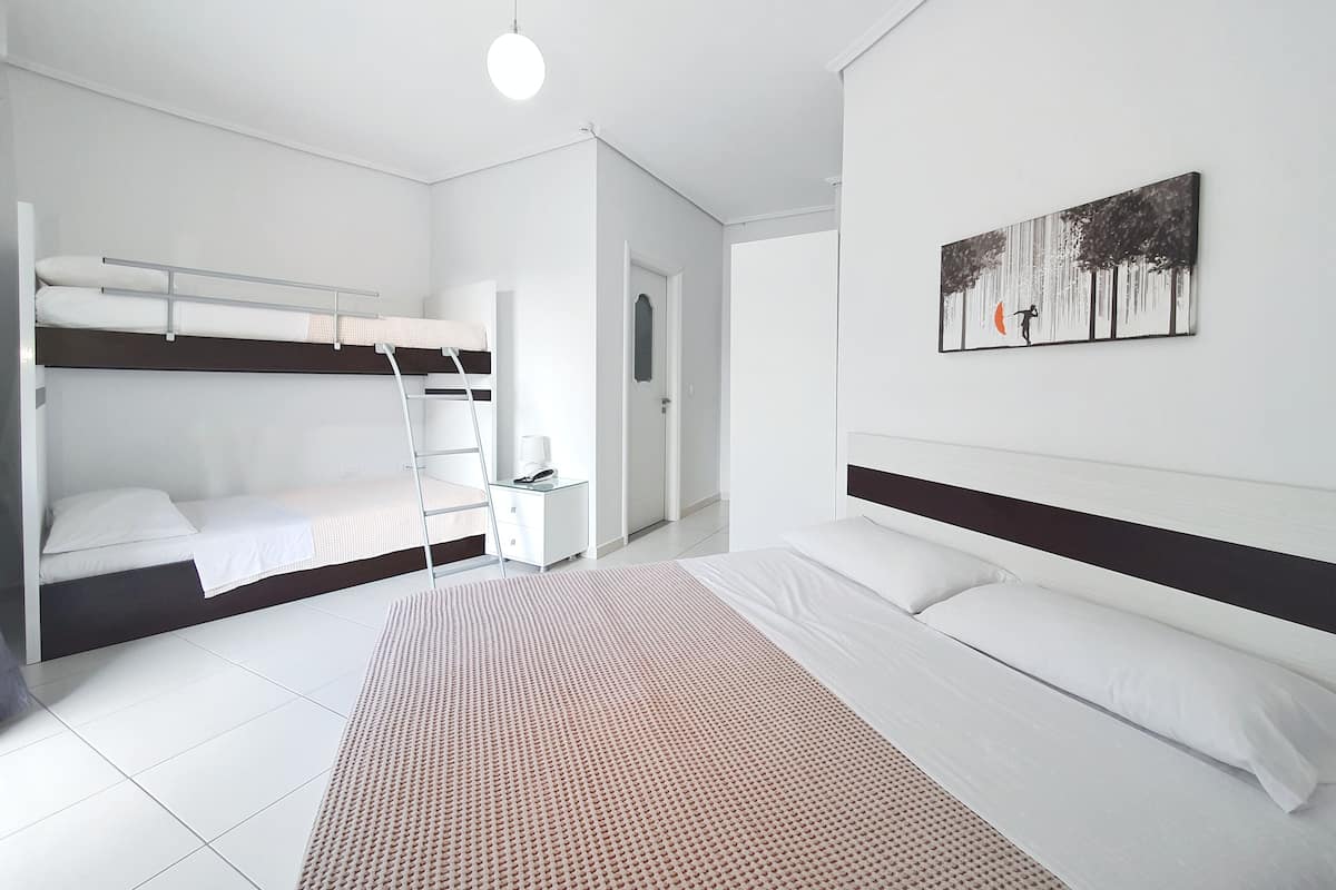 Un dormitorio con literas, una mesita de noche, una cama grande y un cuadro en la pared.