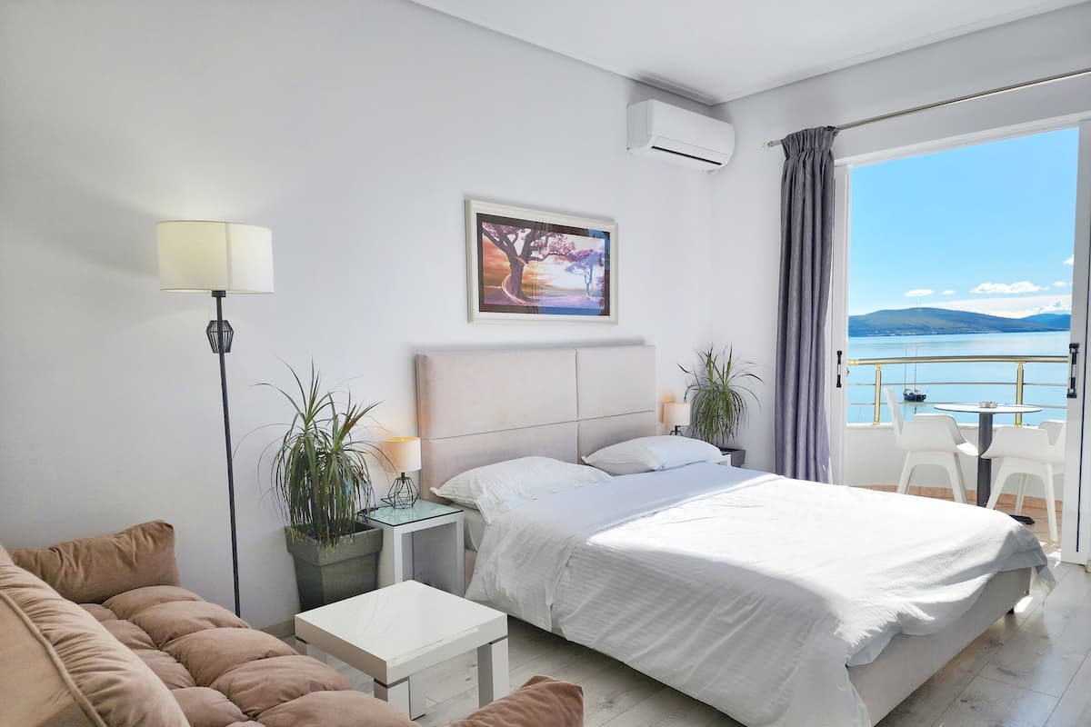 Habitación de hotel moderna con cama, sofá, una mesita y vista al mar.