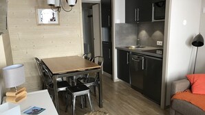 A modern kitchen with dark cabinets, a wooden dining table, and a small rug.