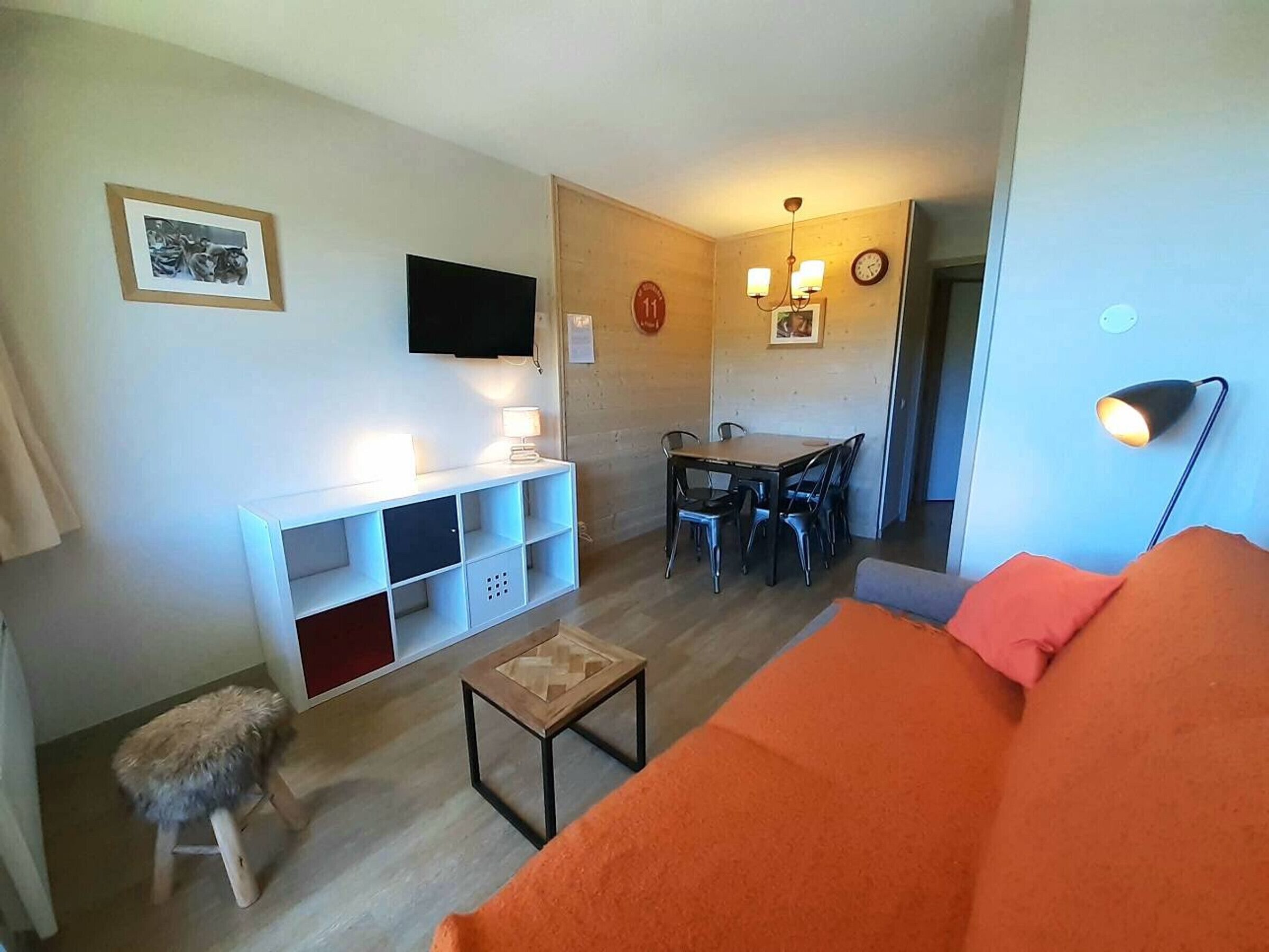 Una sala de estar con un sofá, una mesita, un televisor y un comedor con sillas.