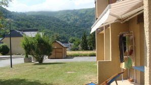 Una propiedad residencial con un cobertizo de madera pequeño, césped y vistas a una cadena montañosa.