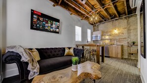 A modern living room with a dark leather sofa, a wooden coffee table, and a mounted Netflix screen. - The Westlake (Toronto)