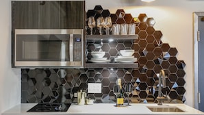 A modern kitchen with a built-in microwave, a sink, and a countertop with a hexagonal backsplash. - The Westlake (Toronto)
