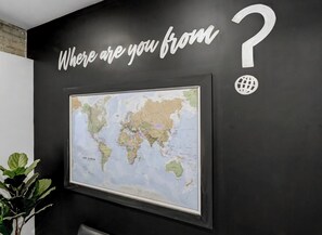 Une carte du monde est affichée sur un mur, avec un point d’interrogation et une icône représentant un globe au-dessus.