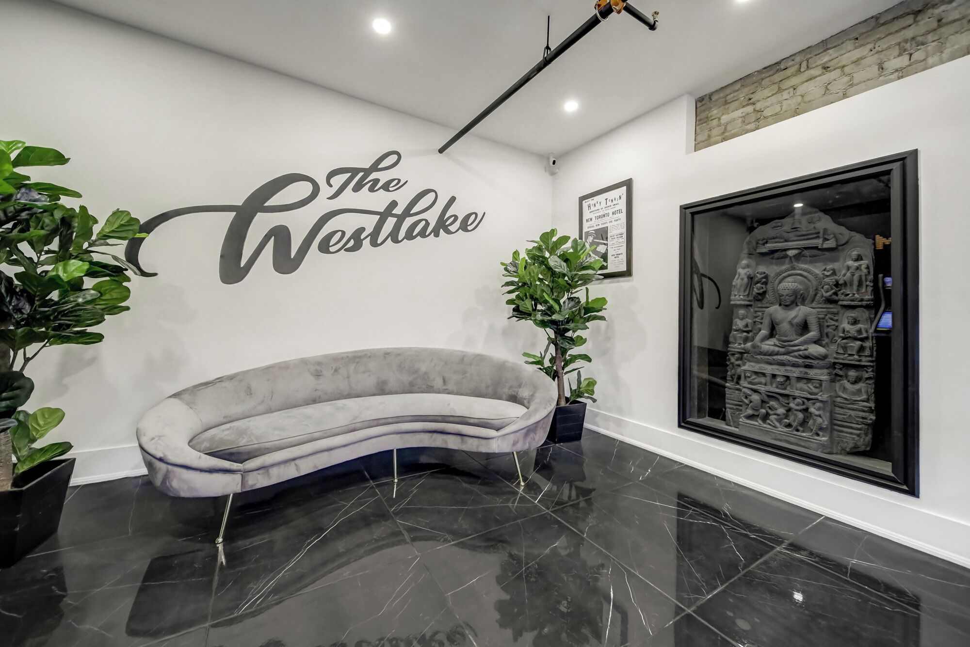 A modern interior with a curved sofa, a Buddha statue, and a sign reading 'The Westlake.'