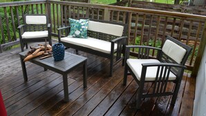 Une terrasse en bois aménagée avec du mobilier d’extérieur, notamment un banc et des chaises avec des coussins.