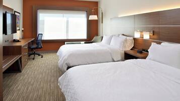 A hotel room with two beds, a desk, a chair, a TV, and a window.