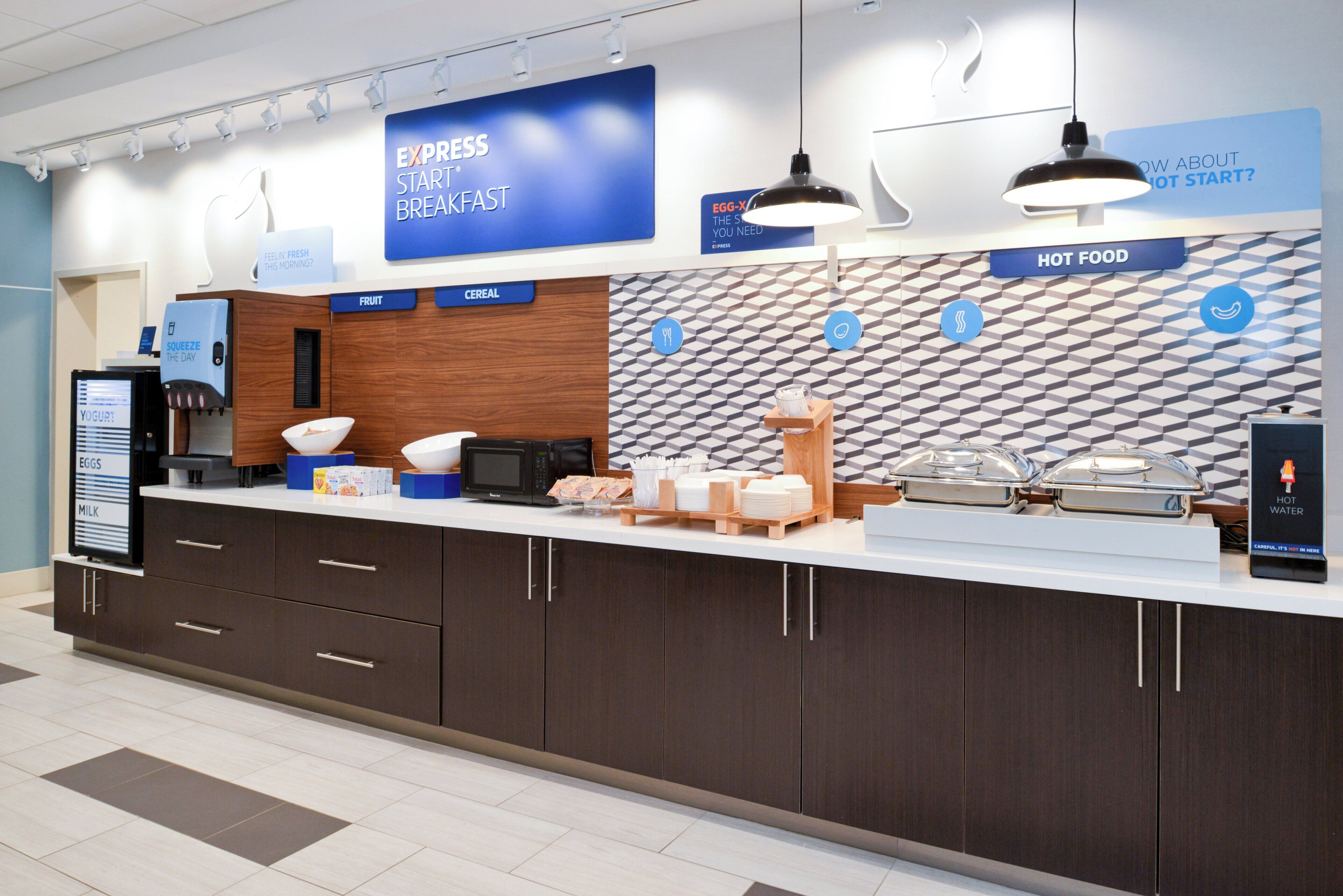 A breakfast station with a digital menu board, a yogurt dispenser, and a microwave.