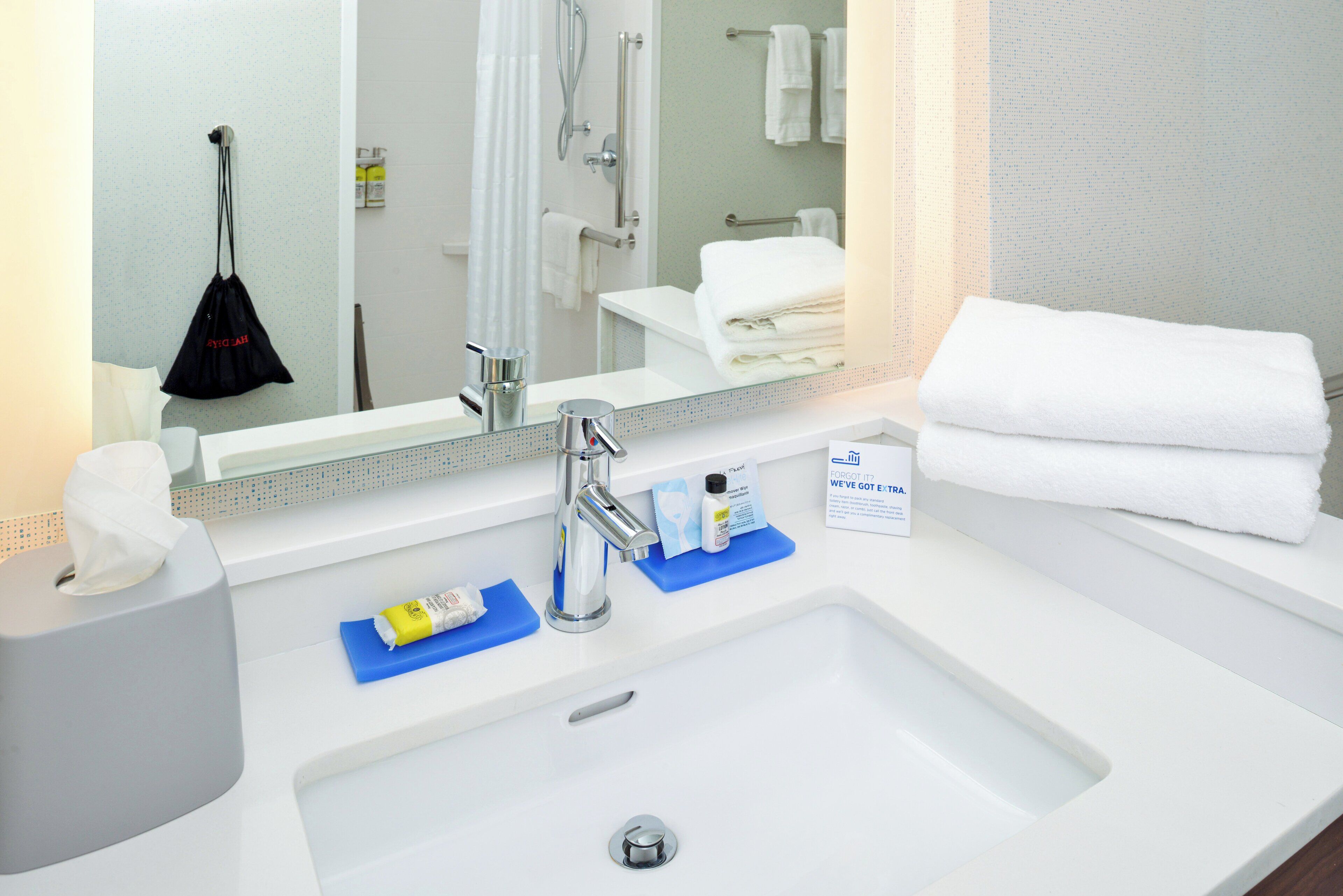 A hotel bathroom with a sink, mirror, and towel rack.