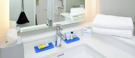 A hotel bathroom with a sink, mirror, and towel rack.