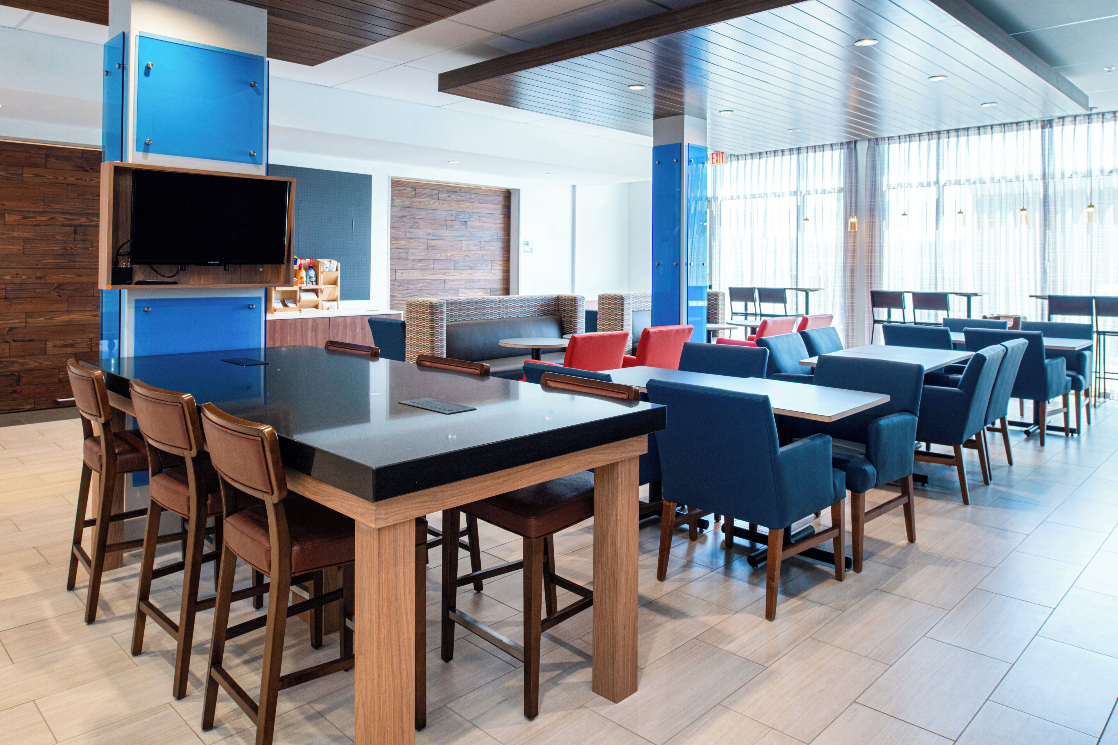 A modern restaurant with a bar area, seating arrangements, and a television.