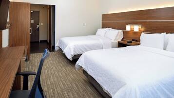 Quarto de hotel com duas camas, uma escrivaninha e uma cadeira.