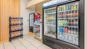 A vending area with a 'Cold Drinks' sign, multiple beverage dispensers, and a shelf with bottled water. - Holiday Inn Express & Suites Medford by IHG (Medford)