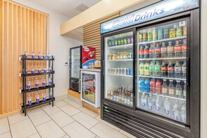A vending area with a 'Cold Drinks' sign, multiple beverage dispensers, and a shelf with bottled water.