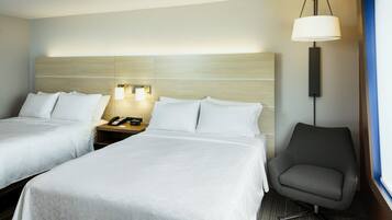 Habitación de hotel con dos camas, una mesita de noche con teléfono, una lámpara de escritorio y una silla.