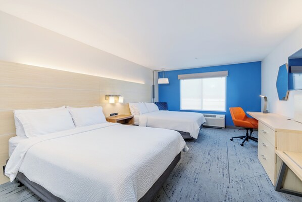 A hotel room with two beds, a desk, an orange chair, and a large window.