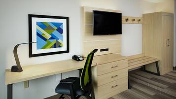 A modern office space with a desk, chair, television, and storage cabinets.