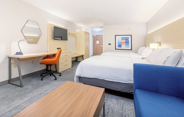 A hotel room with a bed, a desk, a chair, a TV, and a wall-mounted mirror.