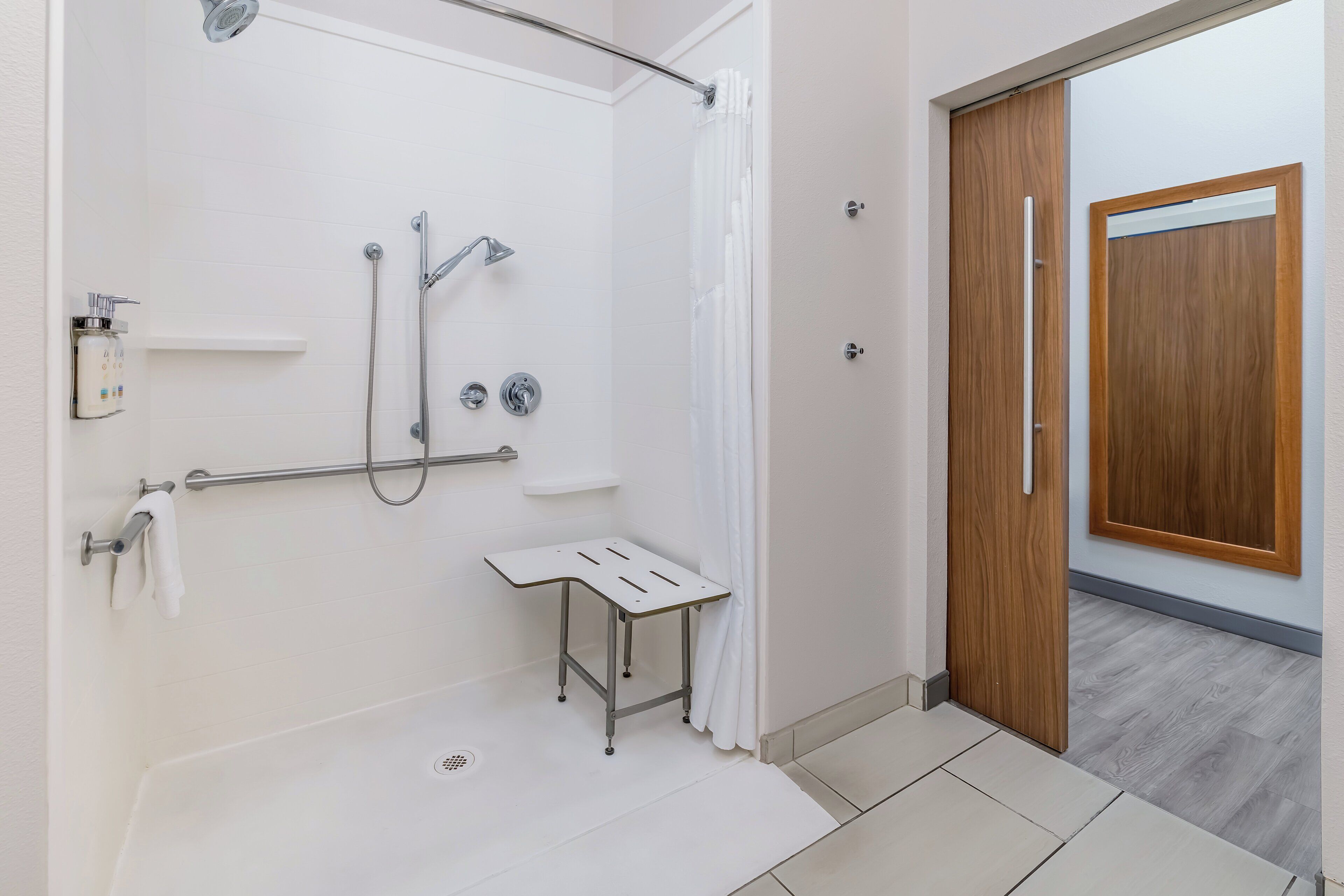 A modern bathroom with a shower, a small table, and a wooden door.