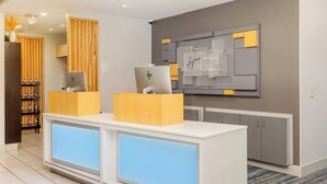 A reception desk with a computer, a wooden partition, and a wall-mounted sign. - Holiday Inn Express & Suites Medford by IHG (Medford)