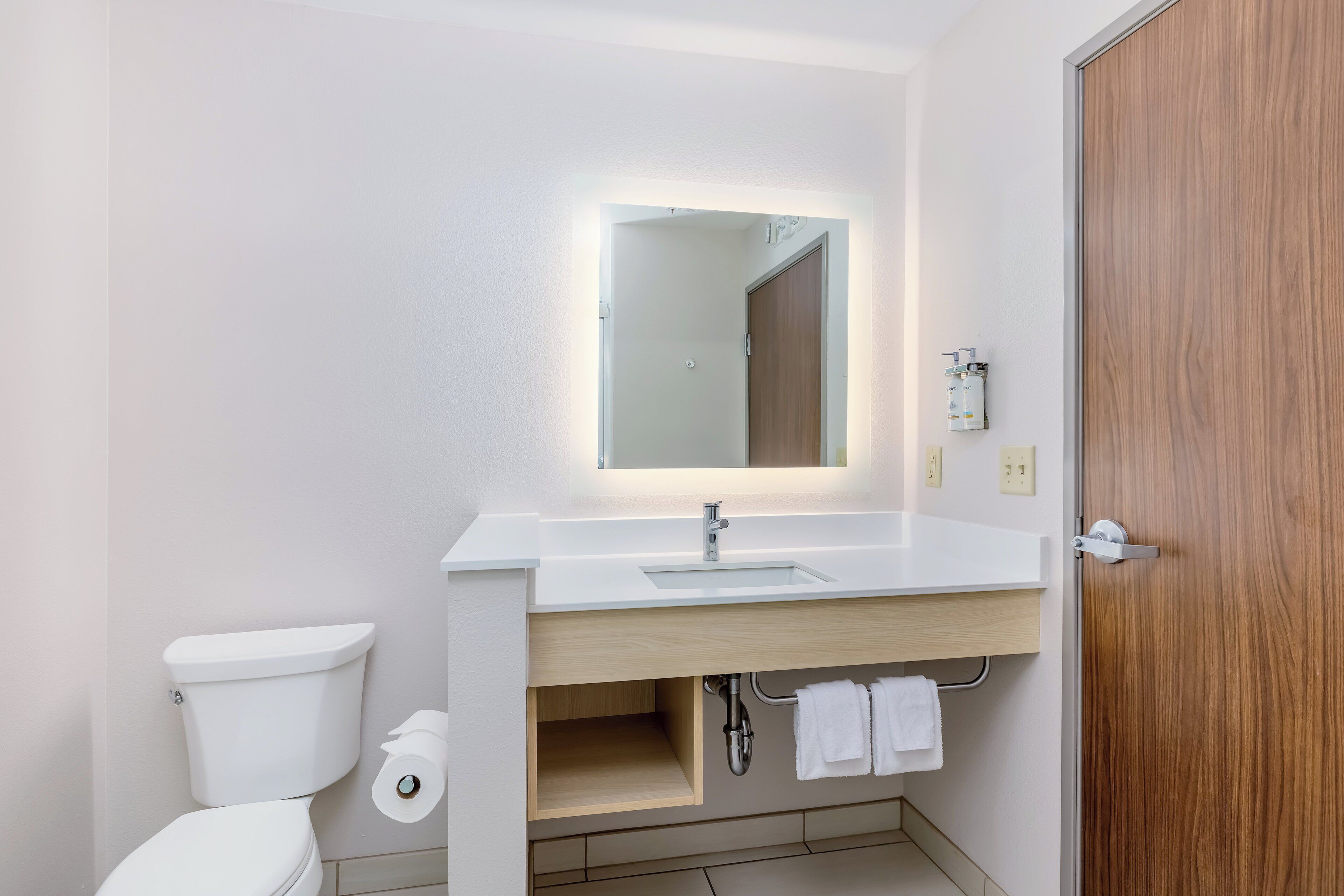 A modern bathroom with a white sink, mirror, and toilet.