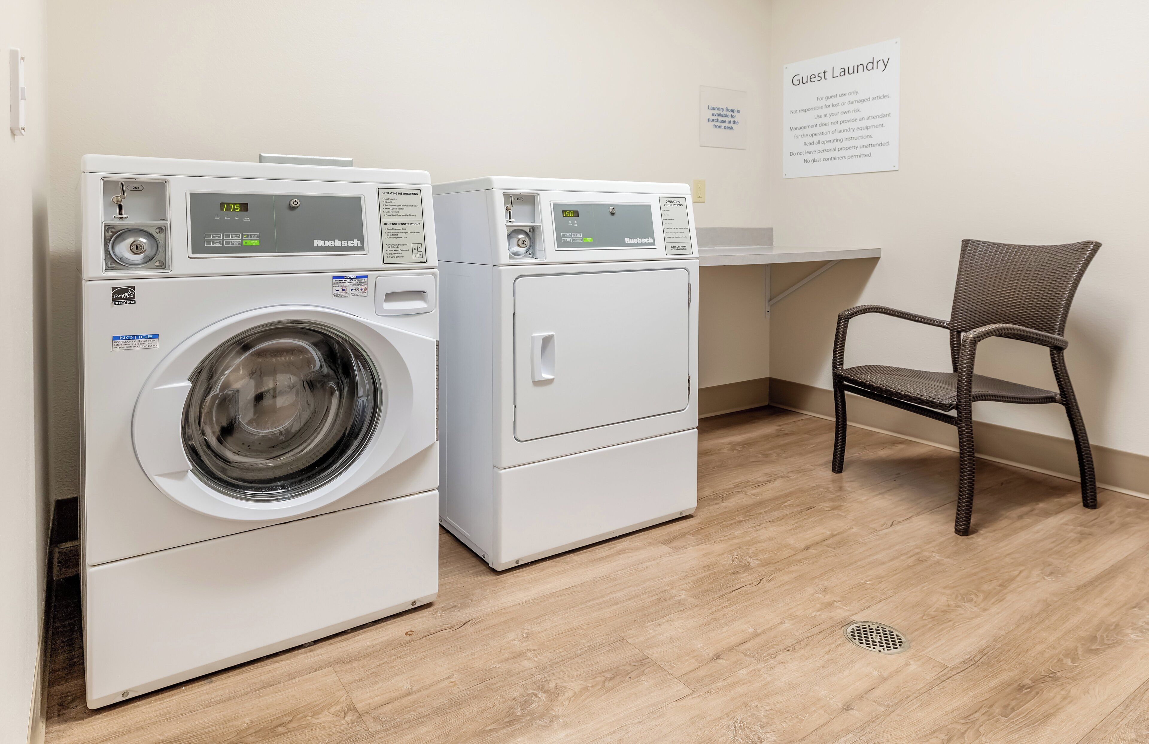 A guest laundry area with two white washing machines, a wicker chair, and a sign indicating laundry use for guests only.