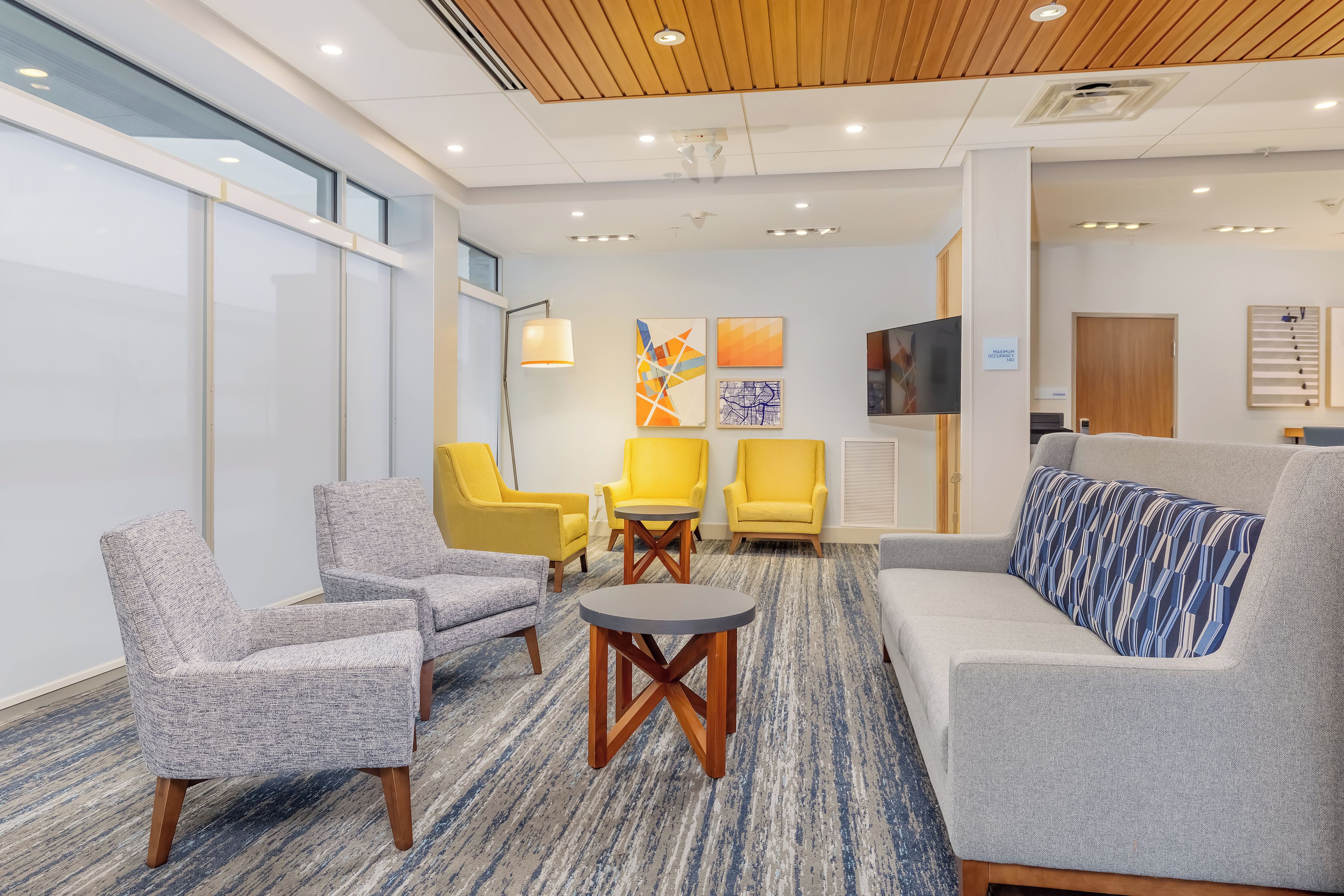 A modern lobby with seating arrangements, a flat-screen TV, and artwork on the walls.