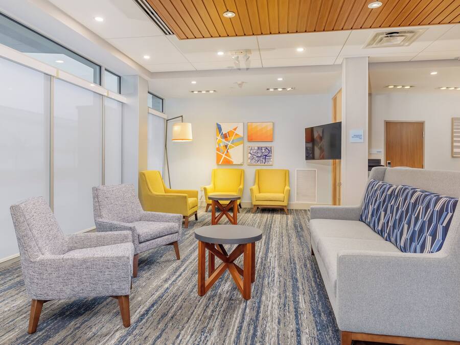 A modern lobby with seating arrangements, a flat-screen TV, and artwork on the walls.