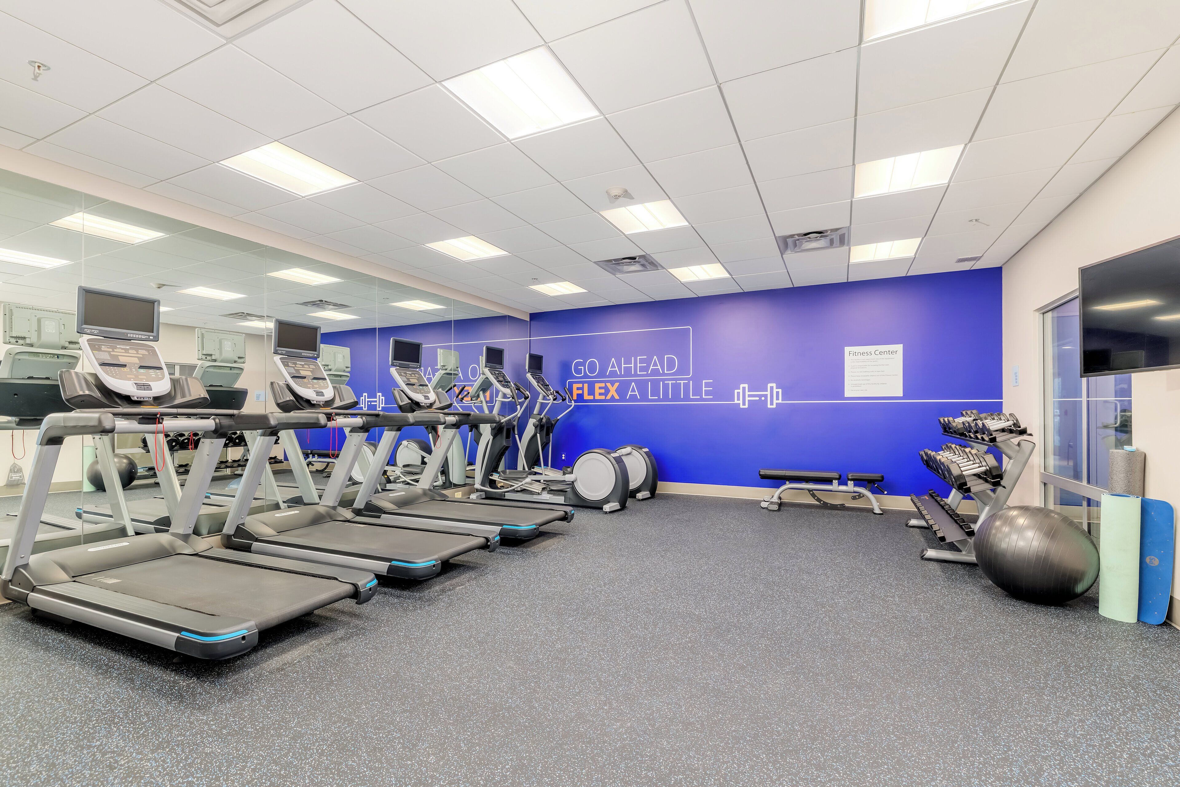 A gym with treadmills, a fitness center sign, and exercise equipment.